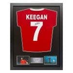 Framed display of a red soccer jersey with 'KEEGAN' and number 7, signed, with two small photos and a plaque underneath.