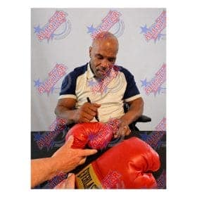 Man signs a red boxing glove at a meet-and-greet with an AllSTAR Signings backdrop behind him