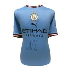 Light blue Manchester City football jersey with club crest, Puma logo, 'Etihad Airways' sponsor, and a signature across the front.