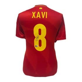 Back view of a red sports jersey with the name XAVI in yellow above a large yellow number 8, with a signature on the number.