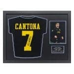 Framed display featuring a black Cantona Manchester United jersey with yellow number 7 and autograph, plus a small photo plaque and caption