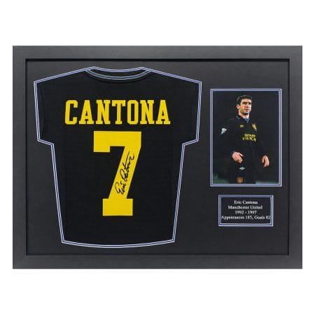 Framed display featuring a black Cantona Manchester United jersey with yellow number 7 and autograph, plus a small photo plaque and caption